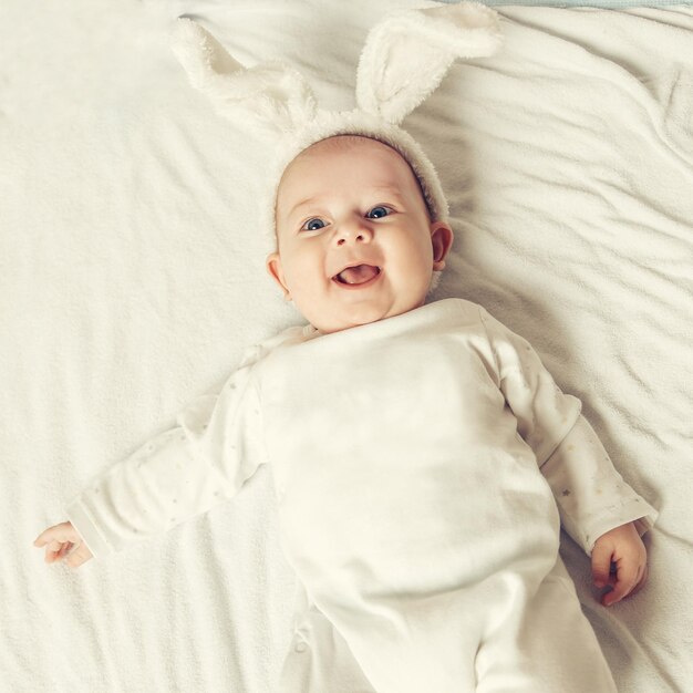 Portrait of adorable smiling baby in Bunny suit lies in the crib