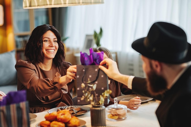 Portrait of adult jewish couple sharing gifts at dinner table in cozy home setting