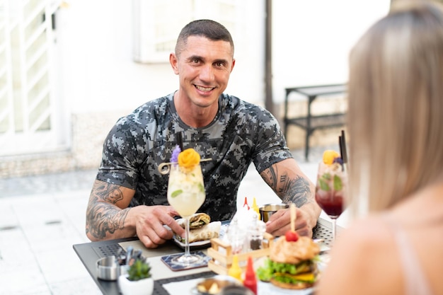 Portrait of Adult Man Eating Tortilla or Burrito Outdoors at Restaurant and Drinking Cocktail