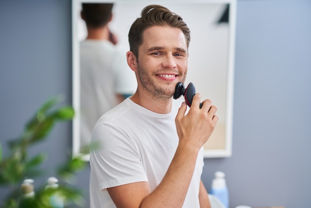 Portrait of adult man shaving in the bathroom