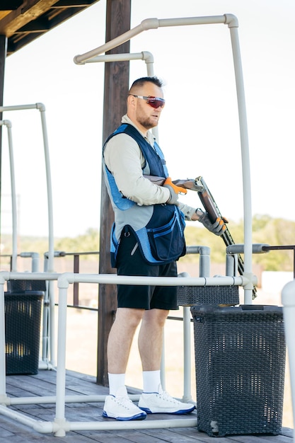 Portrait of adult man in sunglasses and a rifle vest practicing fire weapon shooting