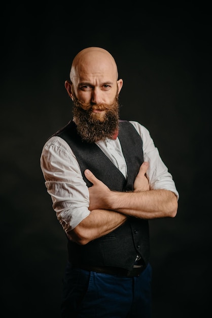 Portrait of an adult stylish bearded man on a black background looking at the camera