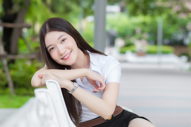 Portrait adult Thai student in university student uniform Asian beautiful girl sitting smiling