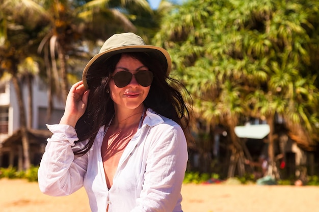 Portrait adult woman in white beachwear hat and sunglasses smiling looking away