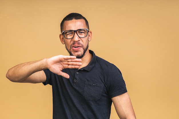 Portrait of African American black man holding hand in stop sign warning and preventing you from something bad looking at the camera with worried expression isolated over beige background