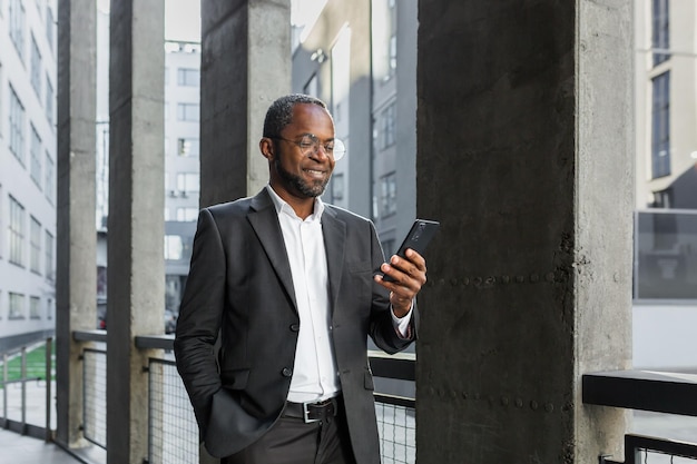 Portrait of an african american businessman banker standing in a suit outside an office building and