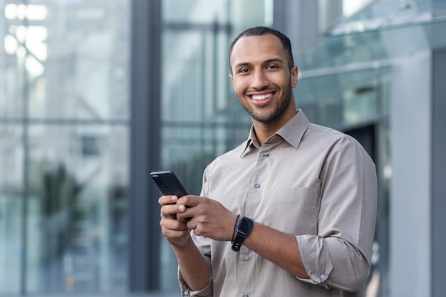 Portrait of african american businessman man holding phone smiling and looking at camera office