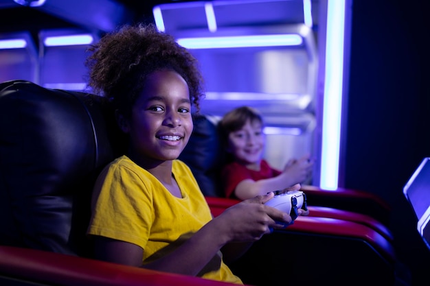 Portrait of African American girl holding console and playing video games with friends