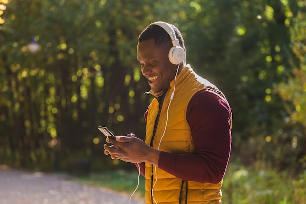 Portrait African american man listens music in autumn park copy space and place for advertising Gadget app and streaming service concept