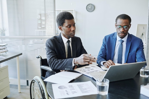 Portrait of african american man with disability in business meeting with partner discussing financi