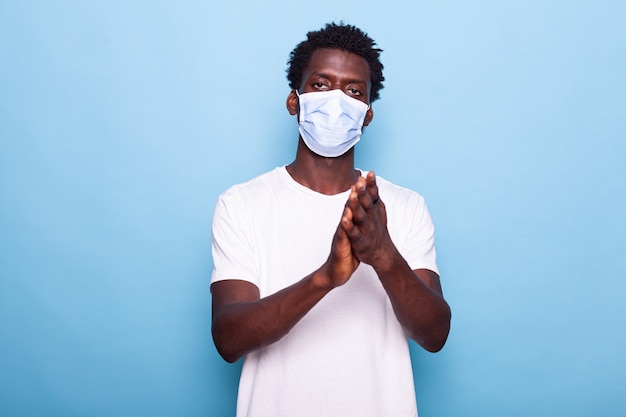 Portrait of african american person clapping and wearing face mask