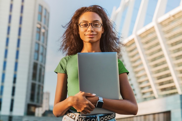 Portrait of african american woman holding laptop computer outdoors