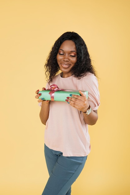 Portrait of african american woman with afro hair wearing pink tshirt posing with gift box