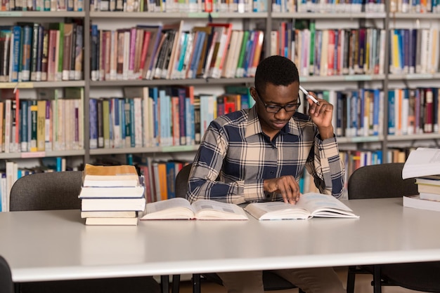 Portrait Of African Clever Student With Open Book Reading It In College Library  Shallow Depth Of Field