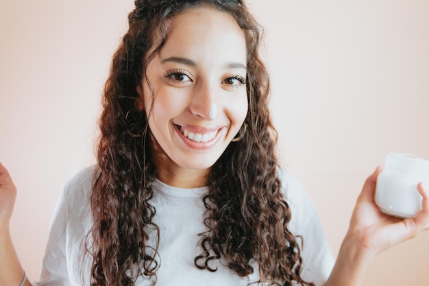 Portrait african curly hair woman applying lotion. Colorful background minimal concept, removable background. Copy space for text, happy aptitude, smiling to camera.