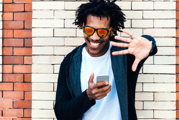 Portrait of afro handsome man using his mobile in the street.