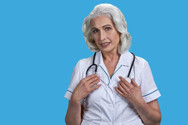 Portrait of aged woman doctor with stethoscope isolated on blue background