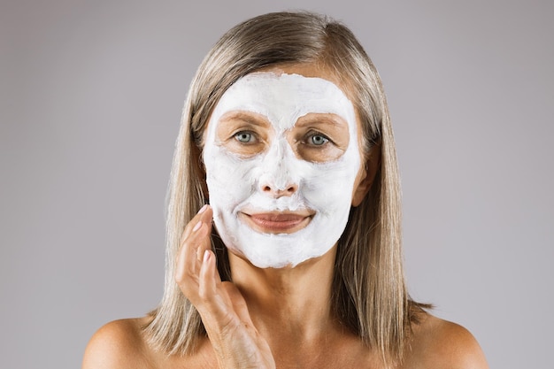 Portrait of aged woman with clay moisturizing mask on face