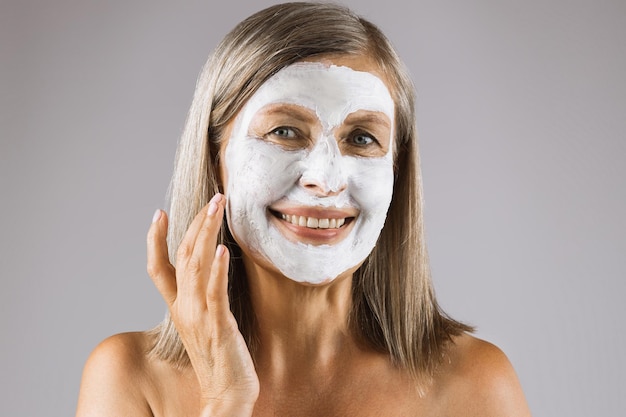 Portrait of aged woman with clay moisturizing mask on face