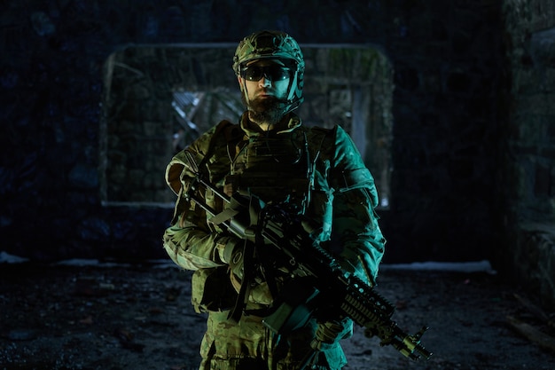 Portrait of airsoft player in professional equipment with machine gun in abandoned ruined building. Soldier with weapons at war