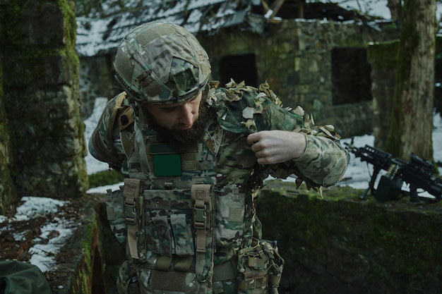 Portrait of airsoft player in professional equipment with machine gun in the forest. Soldier with weapons at war