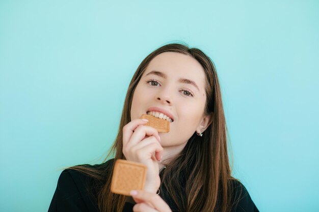 Portrait of alluring redhead woman 20s smiling and eating sweet cookies