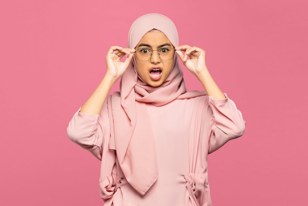 Portrait of amazed young Asian woman holding glasses and looking at the camera