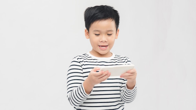 Portrait of an amused cute little kid playing games on smartphone isolated over white background