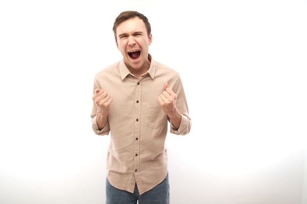 Portrait angry brunette young male screaming isolated on white studio background showing negative emotions