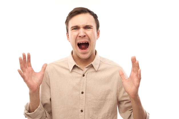 Portrait angry brunette young male screaming isolated on white studio background showing negative emotions