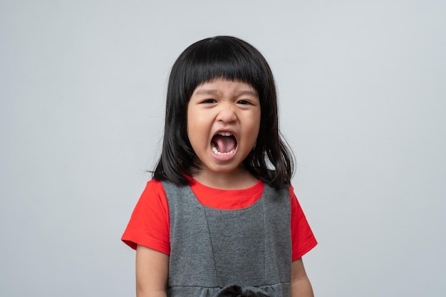 Portrait of angry emotional Asian girl screaming and frustrated shouting with anger crazy and yelling on white background Concept of attention deficit hyperactivity disorder ADHD