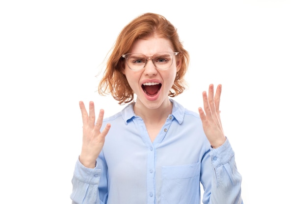 Portrait angry redhead young woman screaming isolated on white studio background showing negative emotionsxA