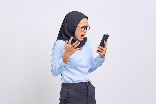 Portrait of angry young Asian woman yelling at mobile phone isolated on white background