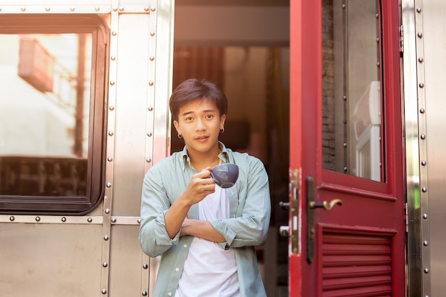 Portrait of asia man hand holding coffee cup relaxing on front door.