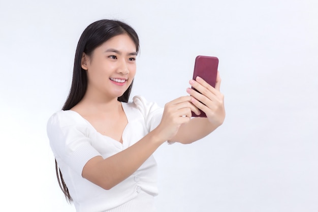 Portrait of asian beautiful woman who has black long hair in white shirt is holding the smartphone