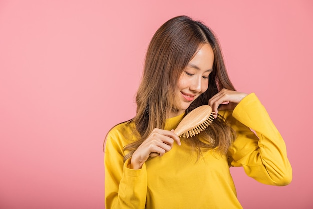 Photo portrait of asian beautiful young woman smile combing her hair happy female long healthy hair with hairbrush brushing hair studio shot isolated