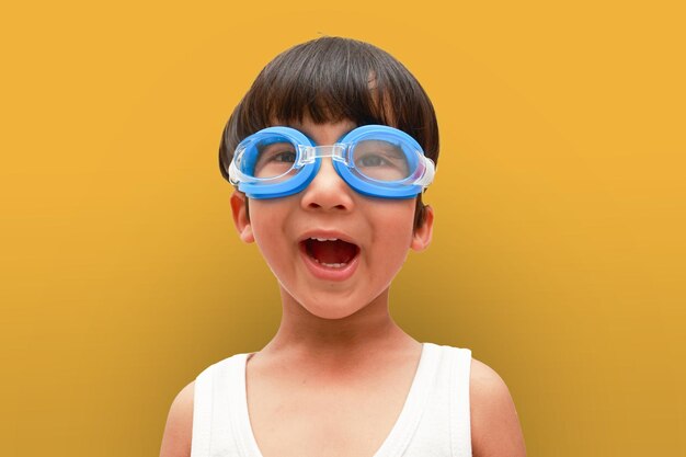 Portrait of Asian boy in swimming goggles happy on yellow background