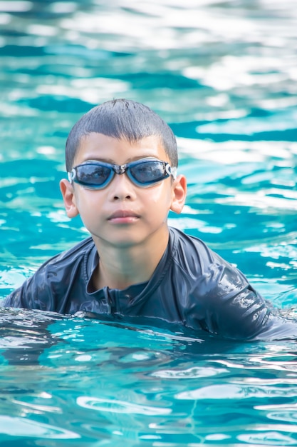 Portrait Asian boy wearing swimming goggles in the pool.