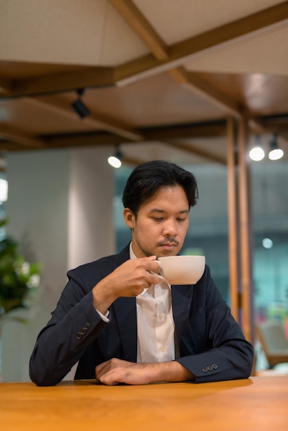 Portrait of Asian businessman in coffee shop drinking coffee