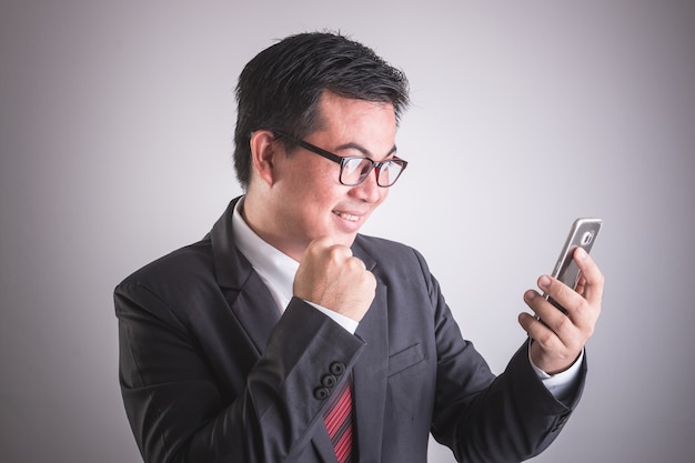 Portrait of Asian businessman holding smartphone. Happy or excited cobcept.