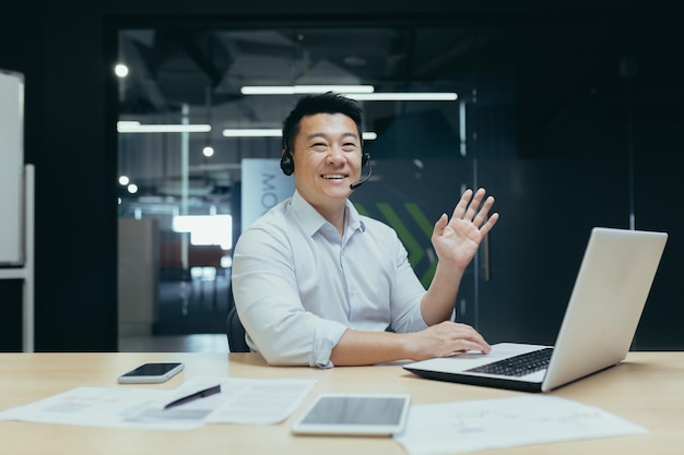 Portrait of asian businessman man looking at camera and waving greeting gesture man with headset for