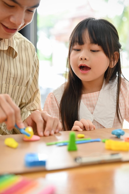 Portrait Asian dad and girl playing at home moulding colorful clay or plasticine together