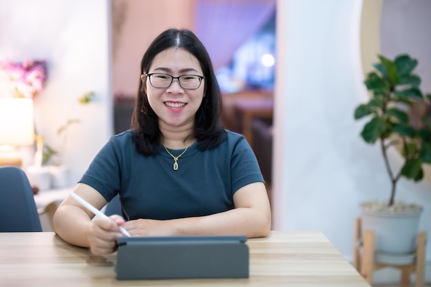 Portrait asian freelance people business female wearing glasses stylish hipster Draw or taking note on digital tablet with electronic pen for browsing internet chatting and blogging in coffee shop