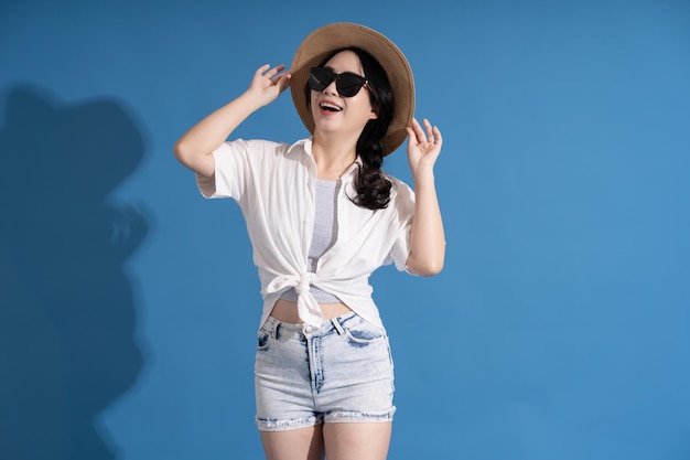 Portrait of asian girl posing on blue background traveling in summer