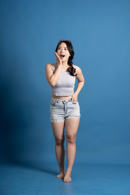 Portrait of asian girl posing on blue background traveling in summer