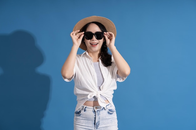 Portrait of asian girl posing on blue background traveling in summer