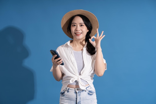 Portrait of asian girl posing on blue background traveling in summer