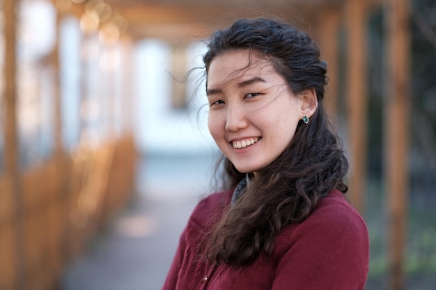 Portrait of an Asian girl in a red sweater in the park alley