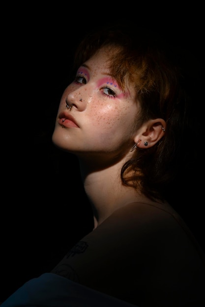 Portrait of asian girl teen with anime cosplay makeup and freckles shadows and light in darkness