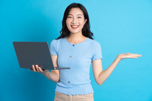 Portrait of asian girl using laptop on blue background